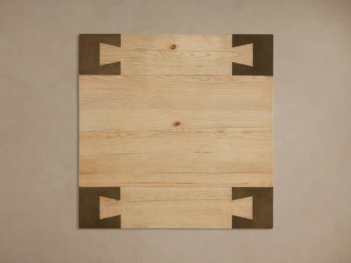Close-up of Telluride End Table's light oak wood top with visible grain and dark oxidized steel leg with geometric cutouts.
