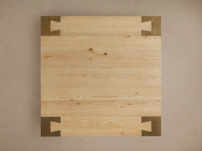 Close-up of a Telluride Square Coffee Table, featuring a light oak wood top with grain details and a dark oxidized steel leg.