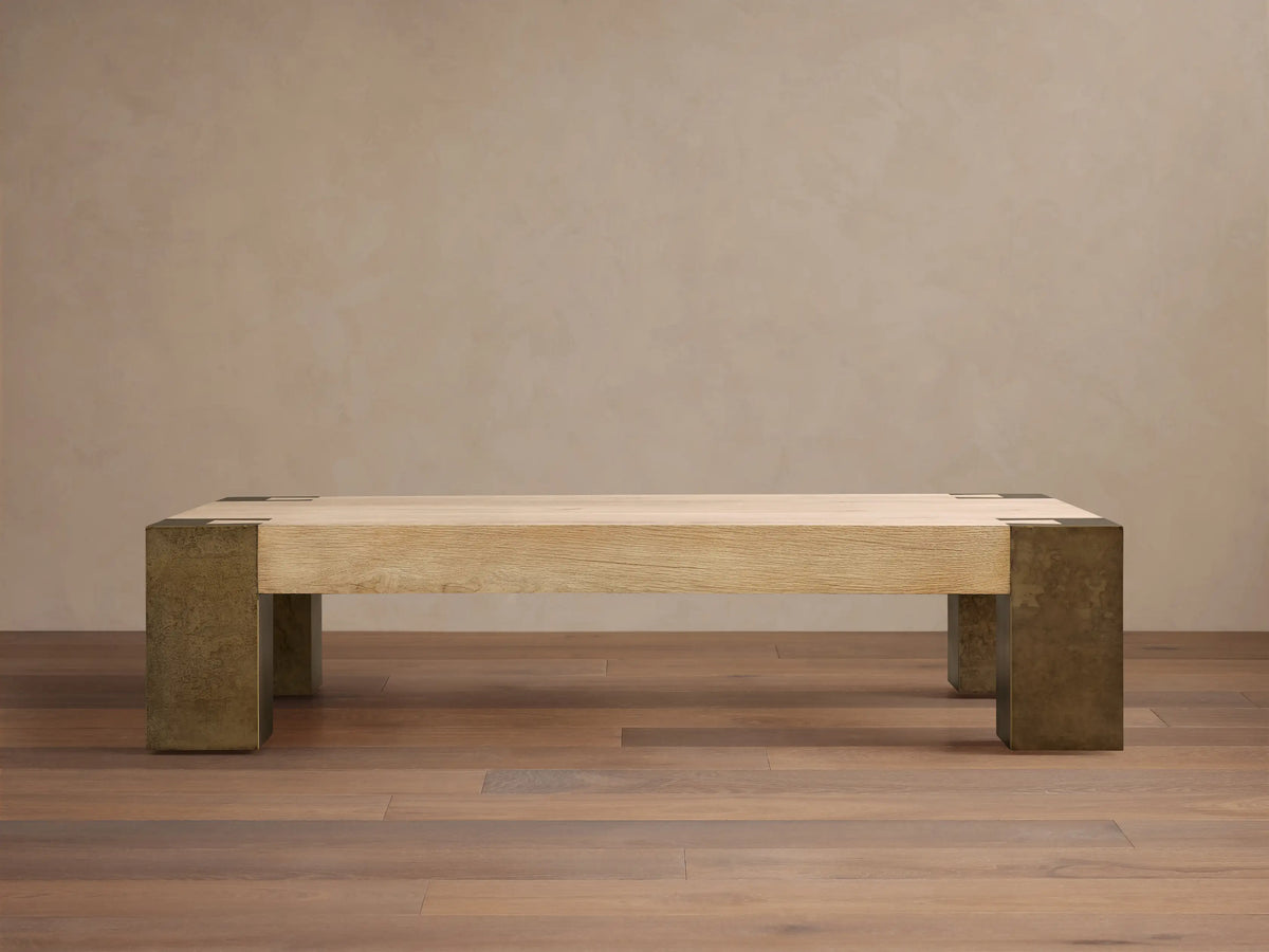Telluride Coffee Table, light oak veneer top with visible grain, naturally oxidized steel legs & corner accents, on a wood floor.