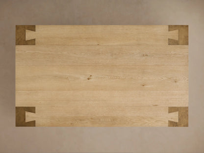 Close-up of Telluride Coffee Table corner. Light oak wood top with grain, joined to dark, weathered steel leg with intricate joint.