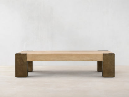 Telluride Coffee Table, light oak veneer top with visible grain, naturally oxidized steel legs & corner accents, on a wood floor.