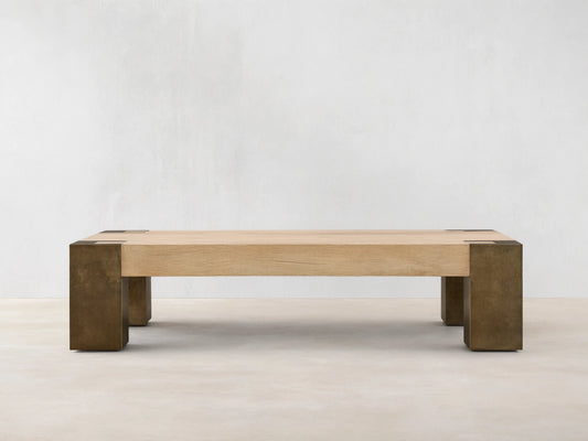 Telluride Coffee Table, light oak veneer top with visible grain, naturally oxidized steel legs & corner accents, on a wood floor.