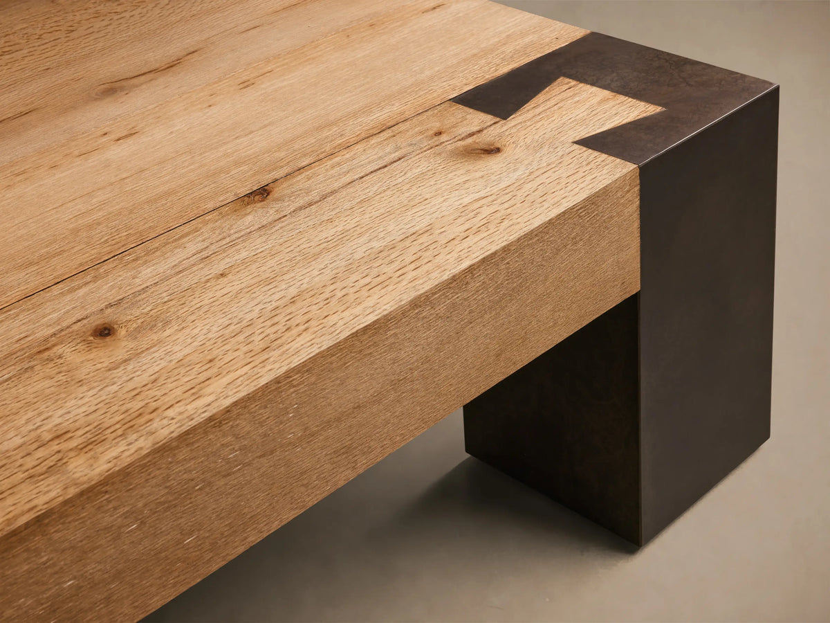 Front view of the Tostada Telluride Coffee Table, featuring a textured light oak veneer top and blocky, mottled oxidized steel legs.