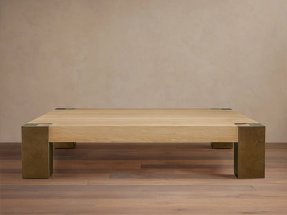 Telluride Square Coffee Table with light oak veneer top & thick, dark oxidized steel corner legs. On wood floor against a light wall.