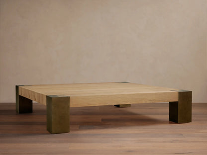 Telluride Square Coffee Table with light oak veneer top & thick, dark oxidized steel corner legs. On wood floor against a light wall.