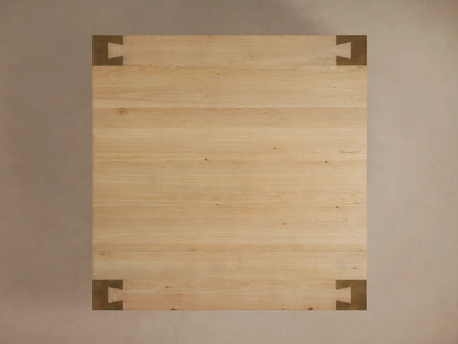 Light oak wood top of Telluride Square Coffee Table with visible grain, accented by a dark, oxidized steel corner wrap.