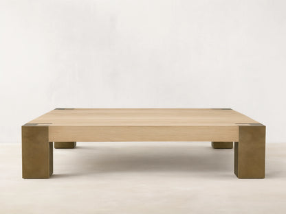 Telluride Square Coffee Table with light oak veneer top & thick, dark oxidized steel corner legs. On wood floor against a light wall.