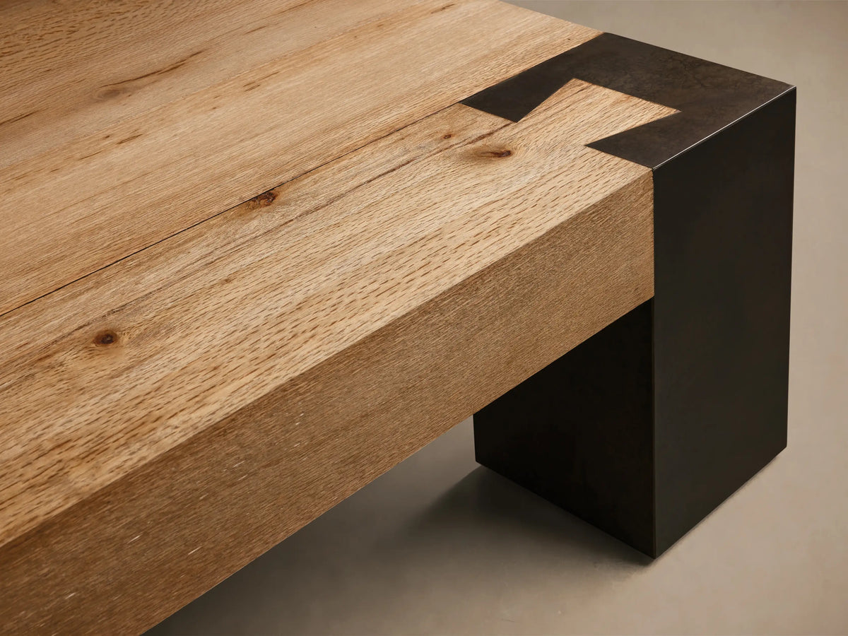 Close-up of the natural oak wood top and dark steel leg of the Telluride Coffee Table, highlighting the precise corner joint.