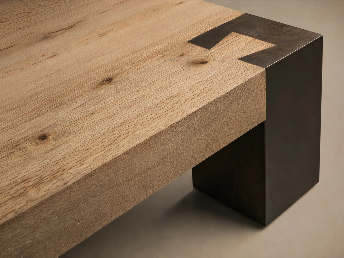 Front view of the Telluride Coffee Table, with a light oak slatted top and dark, oxidized steel block legs.
