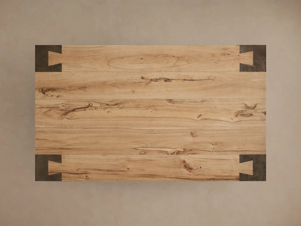 Close-up of the Telluride Coffee Table, showing a light oak wood top and a dark oxidized steel leg with an interlocking joint.