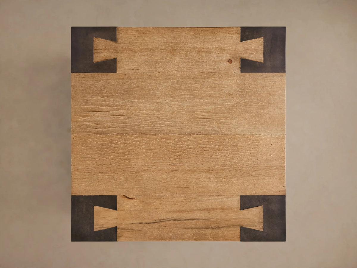 Close-up of the Telluride End Table, featuring light natural oak wood surfaces and dark oxidized steel legs with corner joinery.