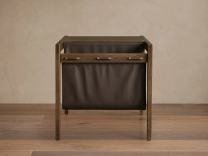 Thorin Magazine Table made of solid oak with a hand-applied finish. Features a dark leather sling on the side for storage.