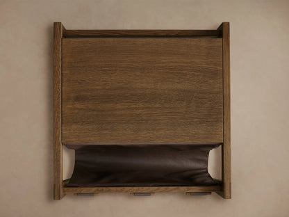 Thorin Magazine Table in solid oak with a brown leather sling held by wood dowels, showcasing a natural finish.