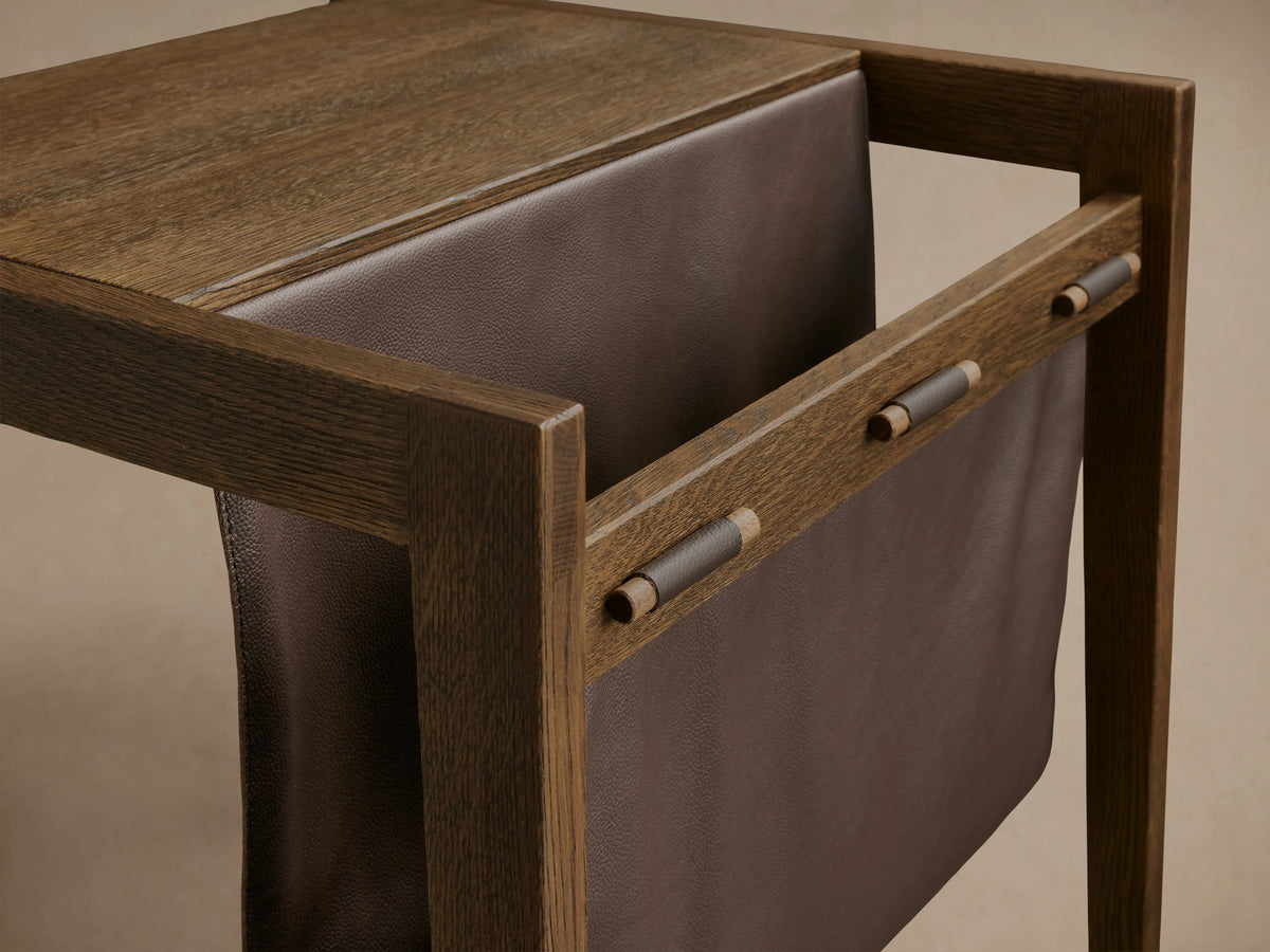Alt text: Top view of the Thorin Magazine Table made of solid oak wood with a brown leather sling underneath, supported by wooden dowels.
