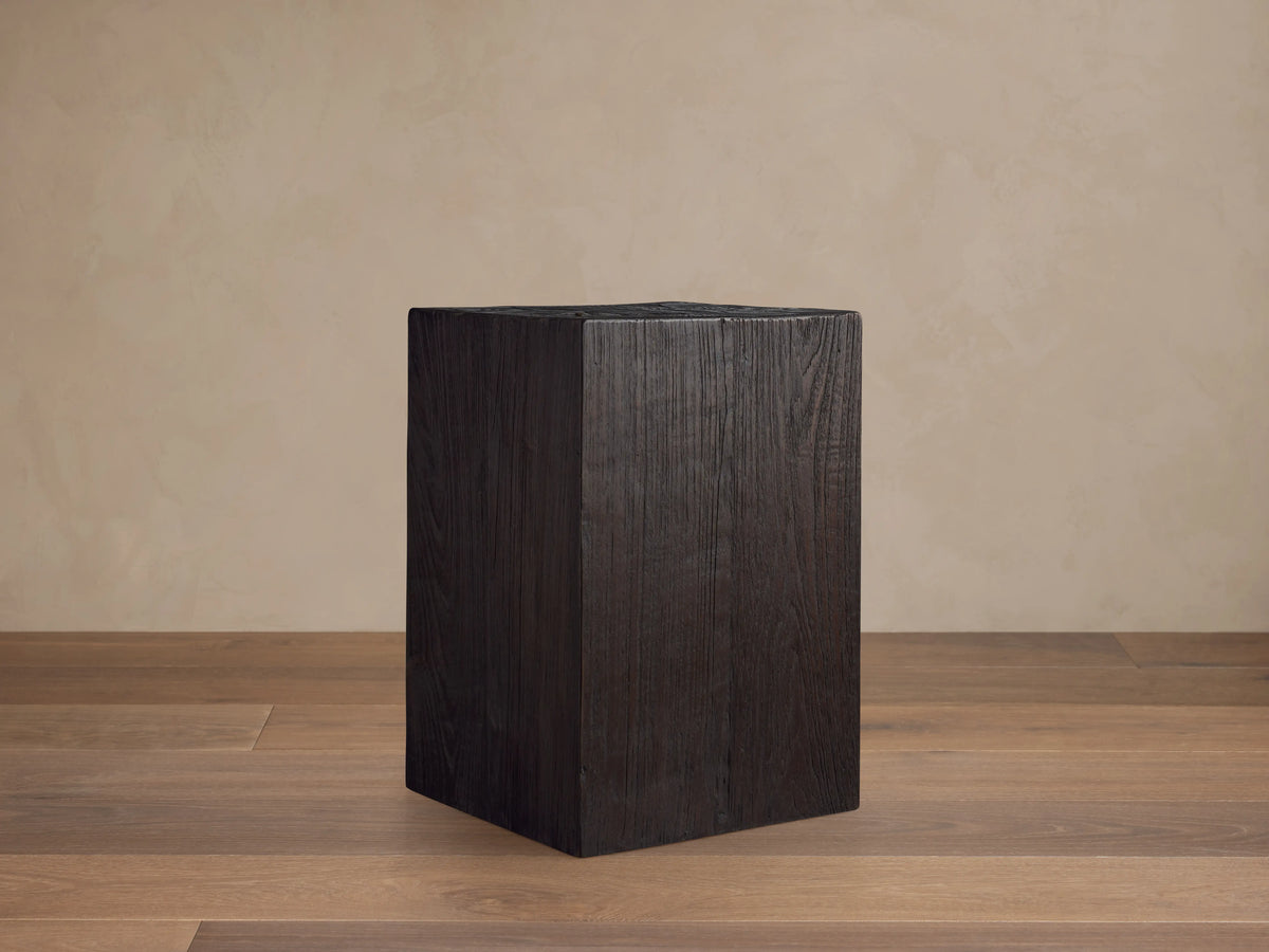 A dark, rectangular Ubud Pedestal made from reclaimed teak wood with a rich black, textured Shou Sugi Ban finish, on wooden floor.