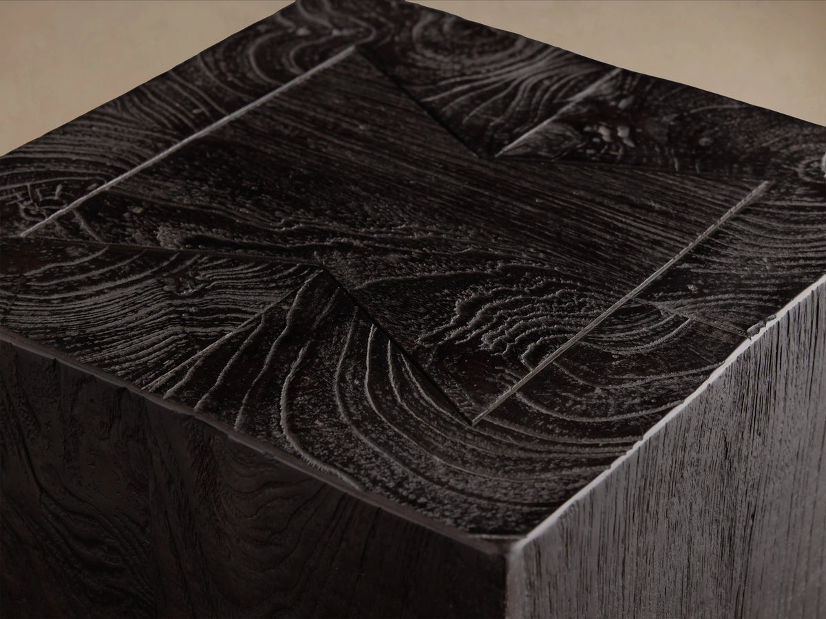 Ubud Pedestal, a rectangular block made of dark reclaimed teak wood with a rich, textured finish. Placed on a wooden floor.