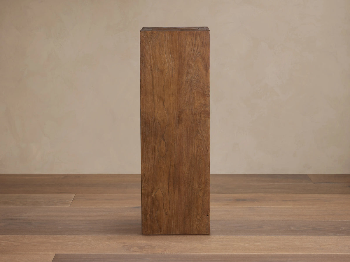 Tall, rectangular Ubud Pedestal made from reclaimed teak wood with warm brown tones and visible natural grain on a wooden floor.
