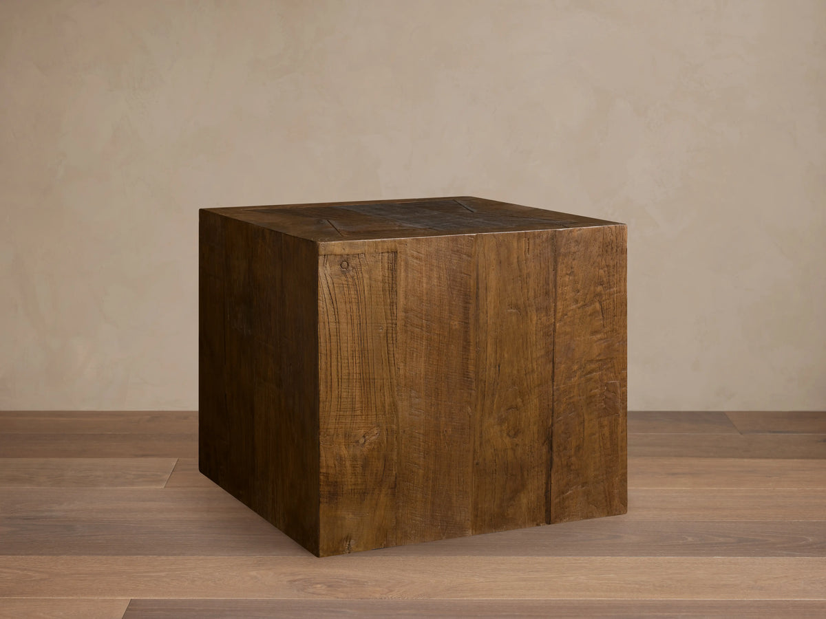 Ubud End Table made from reclaimed teak wood in a cube shape. Natural brown finish with visible grain and knots on a wooden floor.