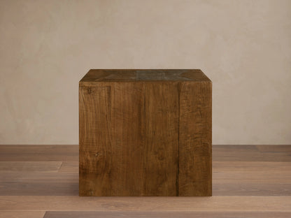 Ubud End Table made from reclaimed teak wood in a cube shape. Natural brown finish with visible grain and knots on a wooden floor.