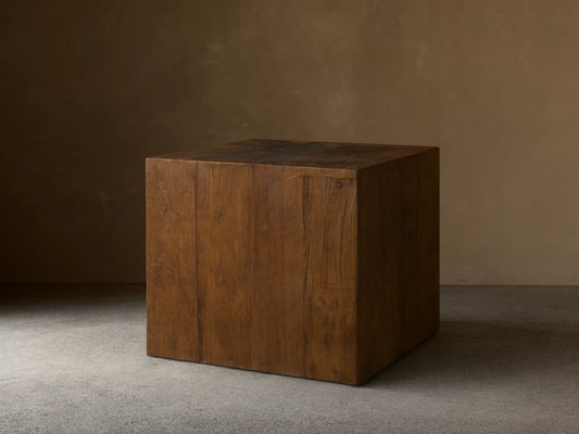 Ubud End Table made from reclaimed teak wood in a cube shape. Natural brown finish with visible grain and knots on a wooden floor.