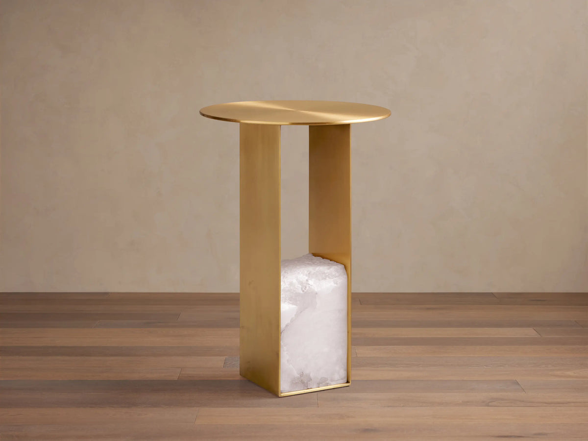 Urben Martini Table, round antique brass top & U-shaped base with white alabaster stone block, centered on wood floor.