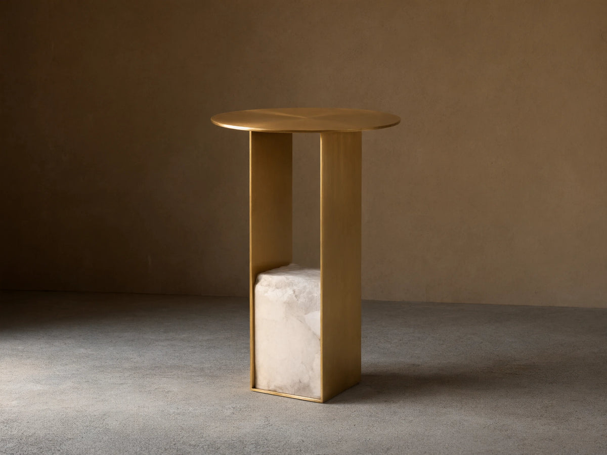 Urben Martini Table, round antique brass top & U-shaped base with white alabaster stone block, centered on wood floor.