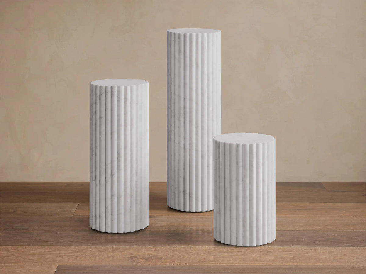 Close-up of a white marble side table, featuring a scalloped top edge, fluted sides, and subtle gray veining.