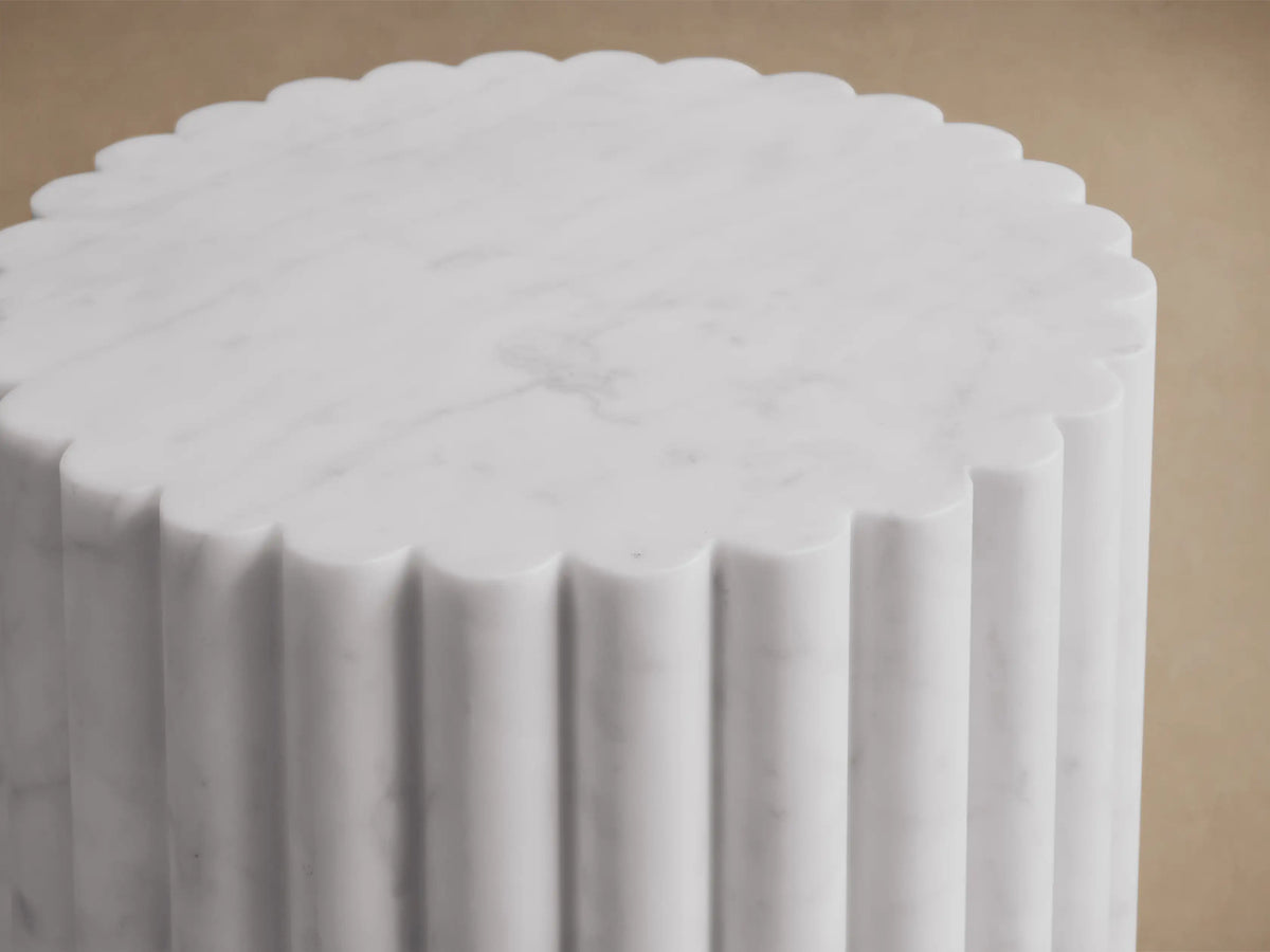Front view of a white marble cylindrical pedestal with vertical fluting.