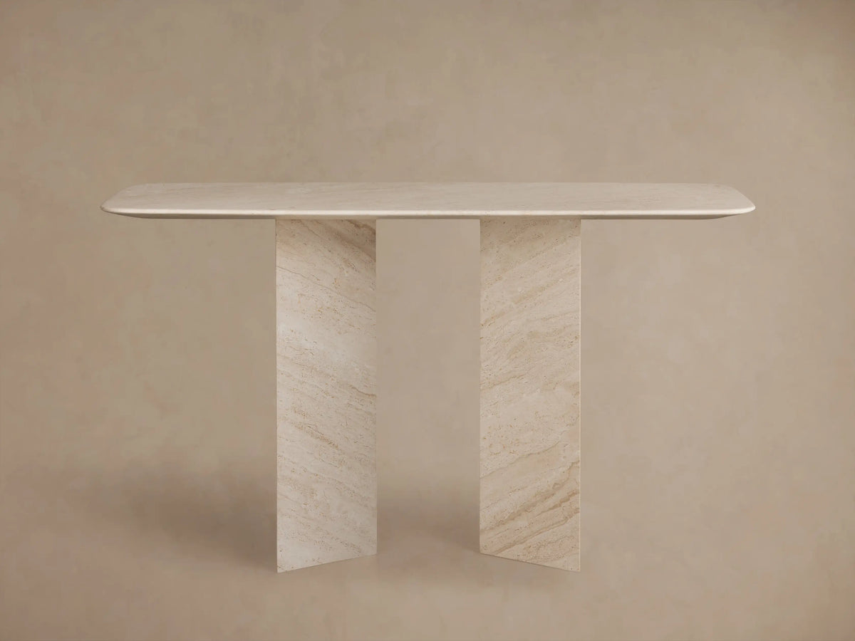 Close-up of Vesuvius Console Table. Light beige natural marble tabletop with rounded edge over angular legs, showing veining.