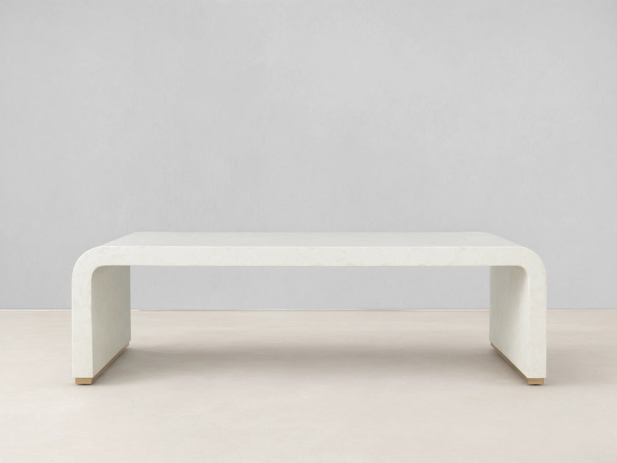 Visola Coffee Table made of ivory-colored resin and camel bone, rectangular with curved edges, on wooden floor, beige background.