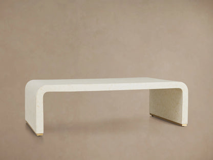 Visola Coffee Table made of ivory-colored resin and camel bone, rectangular with curved edges, on wooden floor, beige background.