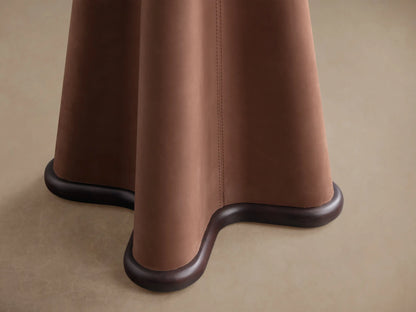 Close-up of the sculptural base of the Volant Leather End Table, featuring saddle brown leather and dark wood trim.
