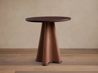 Front view of the Volant Leather End Table with a dark brown wood top and a sculptural brown leather base, featuring vertical stitching.