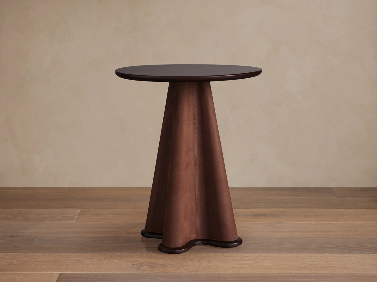 Volant Leather End Table with a dark brown round top and a sculptural leather-wrapped conical base, on a wooden floor.