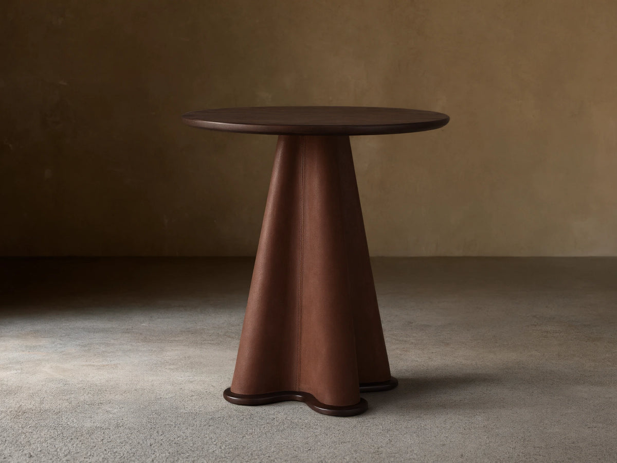 Volant Leather End Table with a dark brown round top and a sculptural leather-wrapped conical base, on a wooden floor.