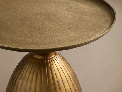 Front view of the gold Zephyr Martini Table, featuring a round top and a ribbed, curved base.