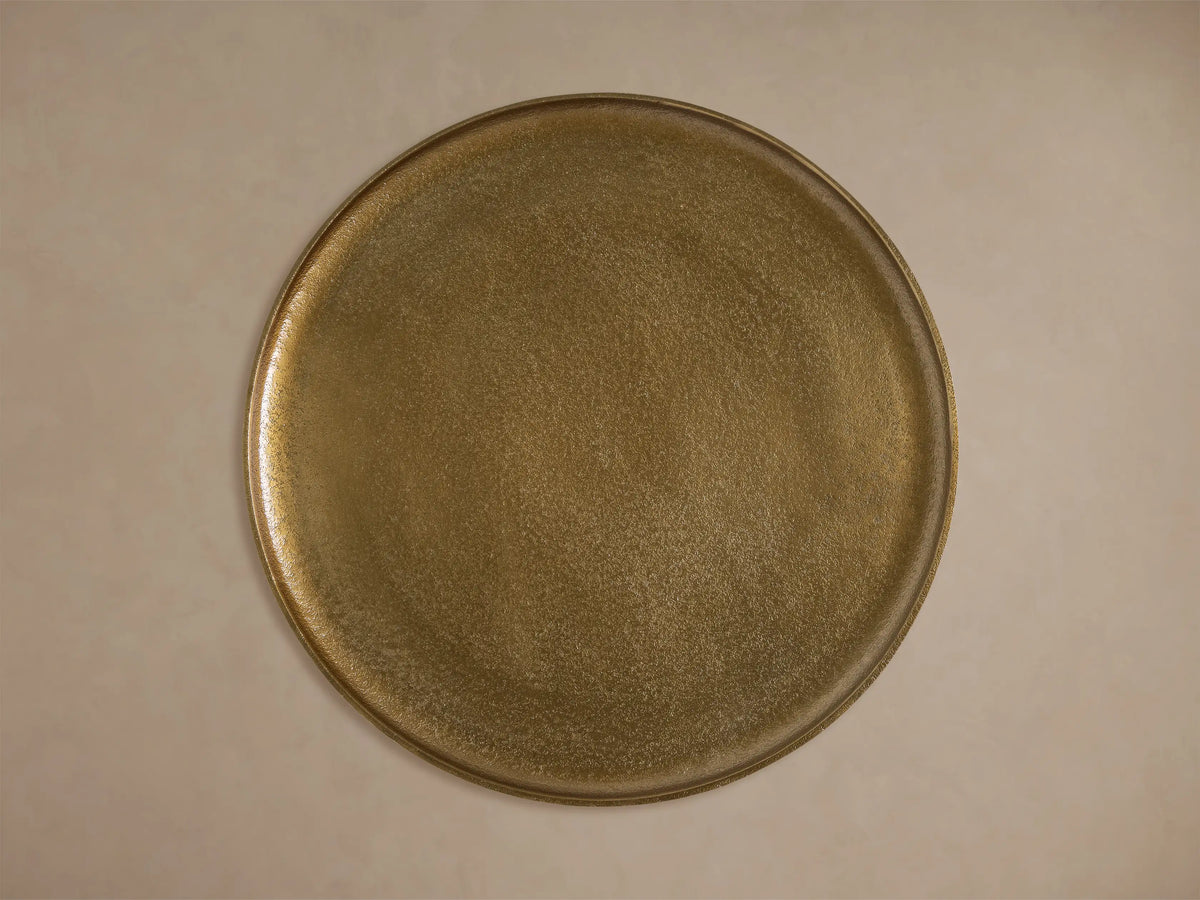 Close-up of the gold Zephyr Martini Table, showing its textured round top and ribbed, curved base.