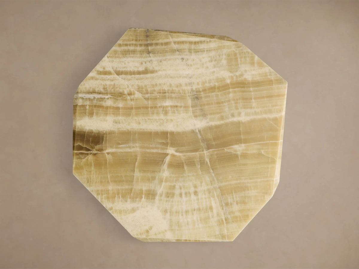 Close-up of the cream onyx Zyra Round Coffee Table, showing its multi-faceted top and two angular pedestal bases.