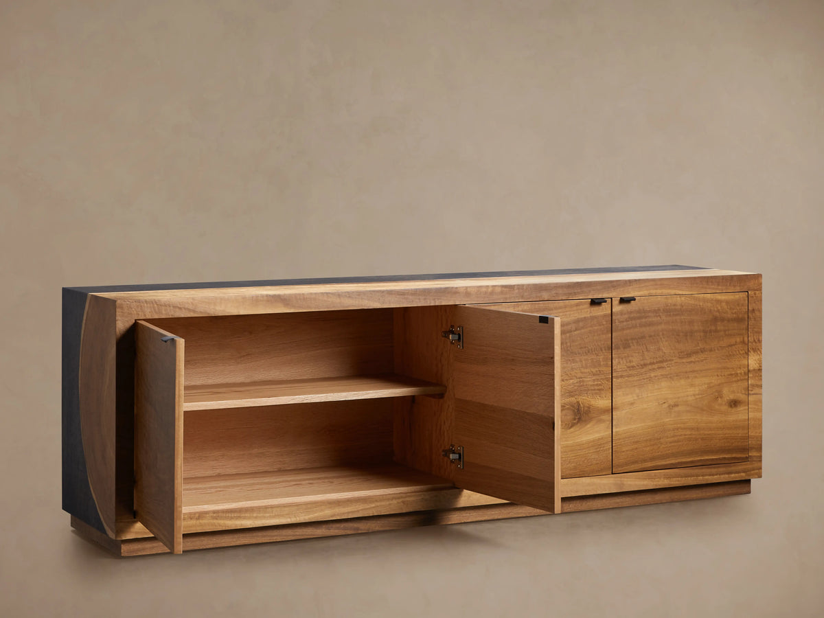 Acacius Media Console with a smooth, curved wooden surface and two cabinet doors, featuring a natural wood grain and dark metal edges.