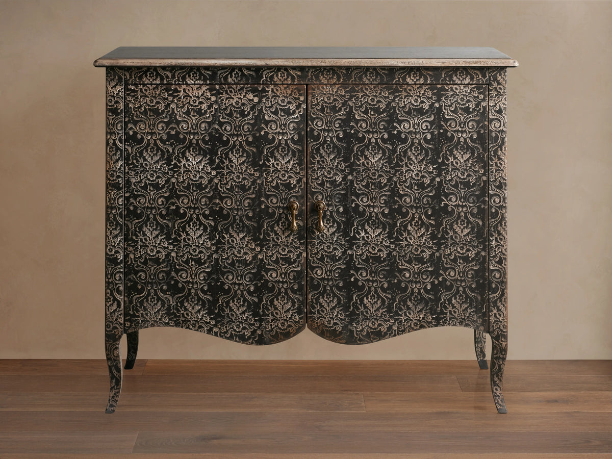 Amalfi Cabinet with intricate, hand-carved floral patterns on antique-finished wood, features two doors and curved legs.