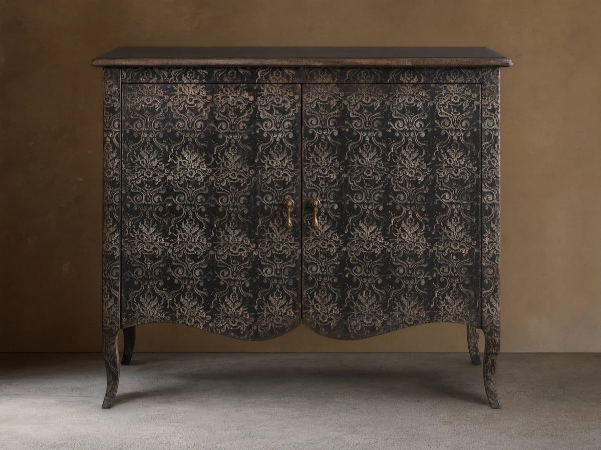 Amalfi Cabinet with intricate, hand-carved floral patterns on antique-finished wood, features two doors and curved legs.