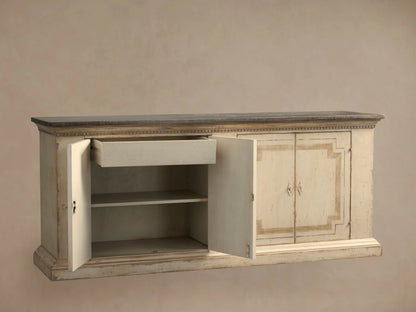 Close-up of the Oriana Buffet, showing its distressed cream finish, geometric design, dark top, and open door with a shelf inside.