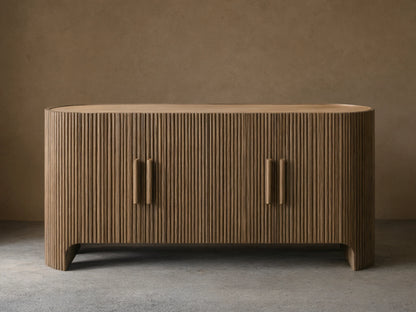 Astor Sideboard with oval marble top, dark oak reeded doors & vertical pulls, against a tan wall on a wood floor.