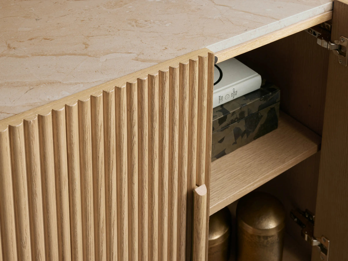 Astor Sideboard: Curved light oak cabinet with reeded detail, white marble top. Right door open revealing two shelves.