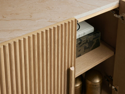 Astor Sideboard: Curved light oak cabinet with reeded detail, white marble top. Right door open revealing two shelves.