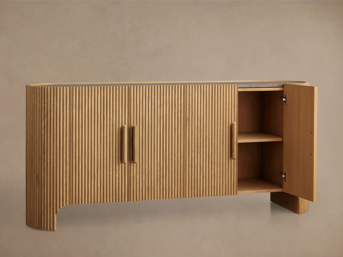 Astor Sideboard made of oak veneers with solid wood reeding, inset marble top, and open cabinet showing shelves and a soft-close door.