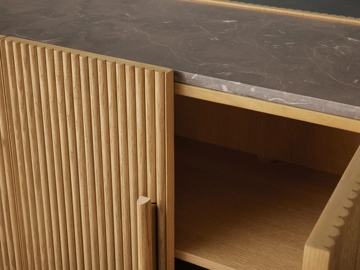 Astor Sideboard with open soft-close door, showing shelves. Oak veneer with vertical reeding, natural marble top, and wood pulls.