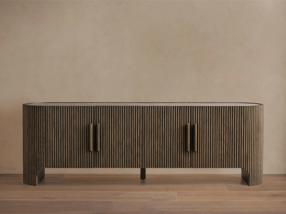 Astor Media Console with oak wood reeding, soft-close doors, and wooden pulls with brass accents. Inset marble top.
