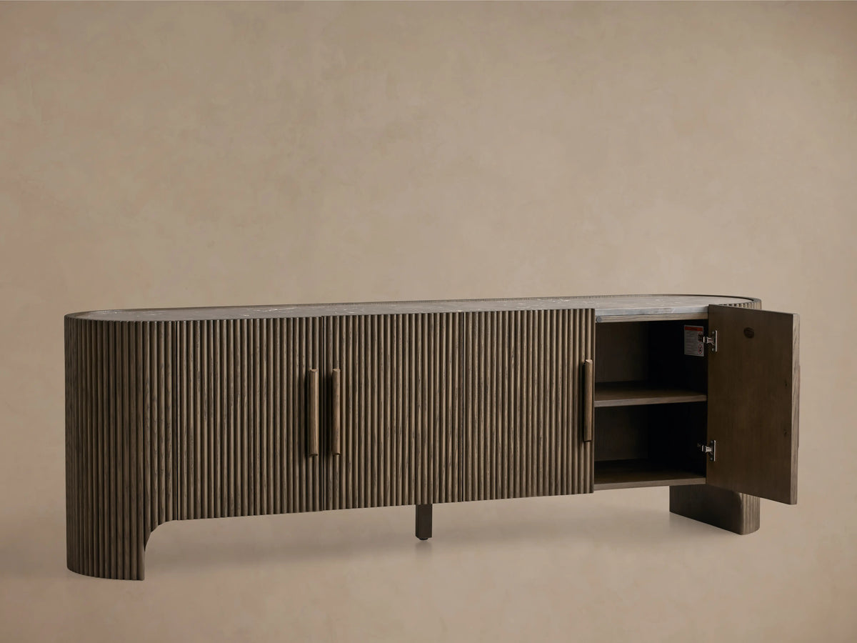 Astor Media Console with oak wood reeding, soft-close doors, and wooden pulls with brass accents. Inset marble top.