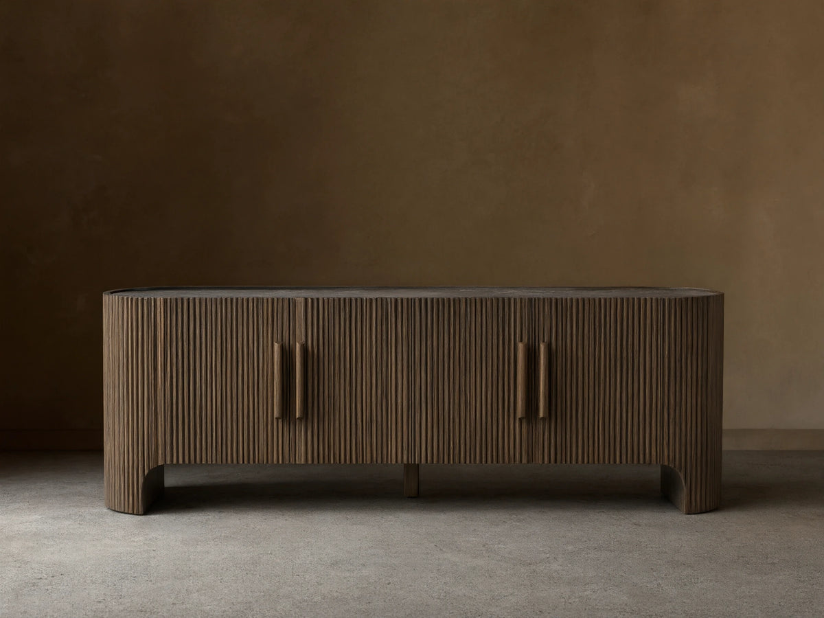 Astor Media Console with oak wood reeding, soft-close doors, and wooden pulls with brass accents. Inset marble top.